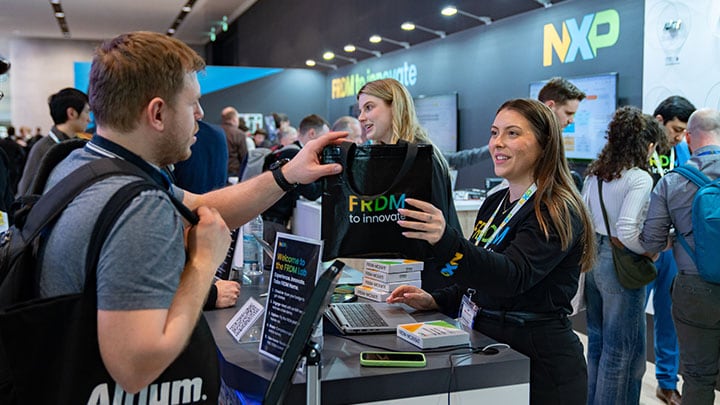 Engineers collaborating inside the NXP FRDM Lab at Embedded World 2026, reviewing development boards and discussing embedded design workflows for edge AI and real‑time control.